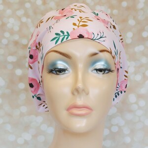 May include: A pink surgical scrub hat with a floral print featuring pink flowers, green leaves, and brown stems.
