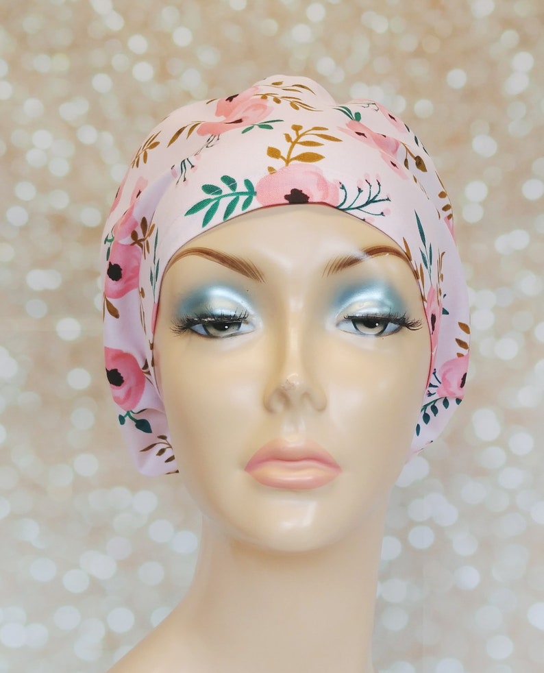 May include: A pink surgical scrub hat with a floral print featuring pink flowers, green leaves, and brown stems.