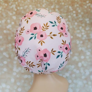 May include: A pink shower cap with a floral pattern featuring pink flowers and gold and green leaves.