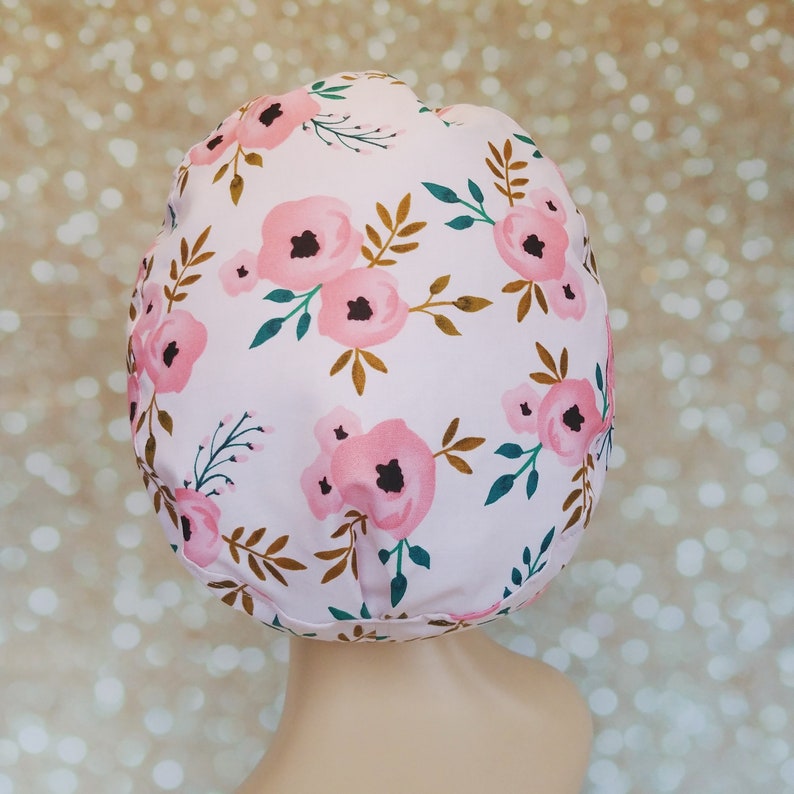 May include: A pink shower cap with a floral pattern featuring pink flowers and gold and green leaves.