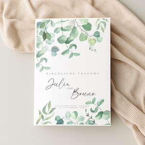 Könnte beinhalten: Eine weiße Hochzeitseinladung mit grünen Aquarell-Eukalyptusblättern und den Namen "Julia und Bruno" in eleganter Schrift. Der Text "Kirchliche Trauung" steht oben. Datum und Ort sind ebenfalls angegeben.