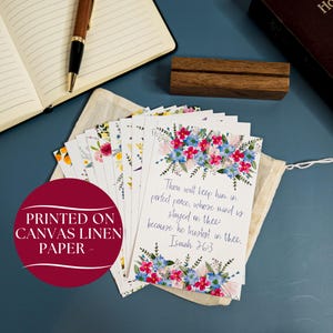 May include: A set of floral cards printed on canvas linen paper. Each card features a different watercolor floral design and a bible verse. The verse on the front card reads: "Thou wilt keep him in perfect peace, whose mind is stayed on thee: because he trusteth in thee. Isaiah 26:3"
