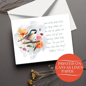 May include: Greeting card featuring a watercolor illustration of a bird perched on a branch with orange and pink flowers. The card includes text from Matthew 6:26 ESV. The card is printed on canvas linen paper.