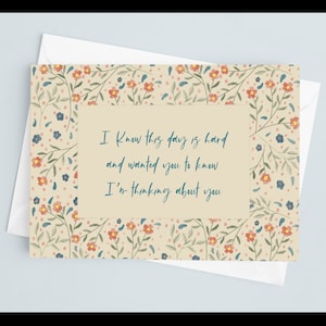 May include: A beige card with a floral pattern border. The card has a blue text message that reads "I know this day is hard and wanted you to know I'm thinking about you."
