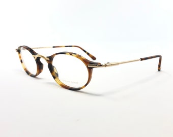 May include: Tortoise shell eyeglasses with gold metal arms. The glasses have round lenses and a subtle tortoise shell pattern.