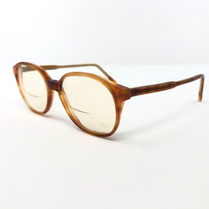 May include: Brown tortoise shell eyeglasses with clear lenses. The glasses have a simple, classic design.