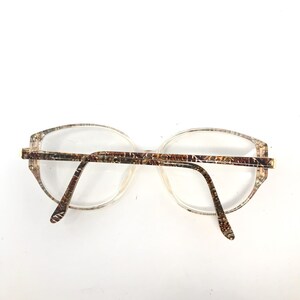 May include: A pair of brown and gold patterned eyeglasses with clear lenses.