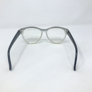 May include: A pair of silver-rimmed eyeglasses with black plastic arms. The glasses have a round shape and clear lenses.