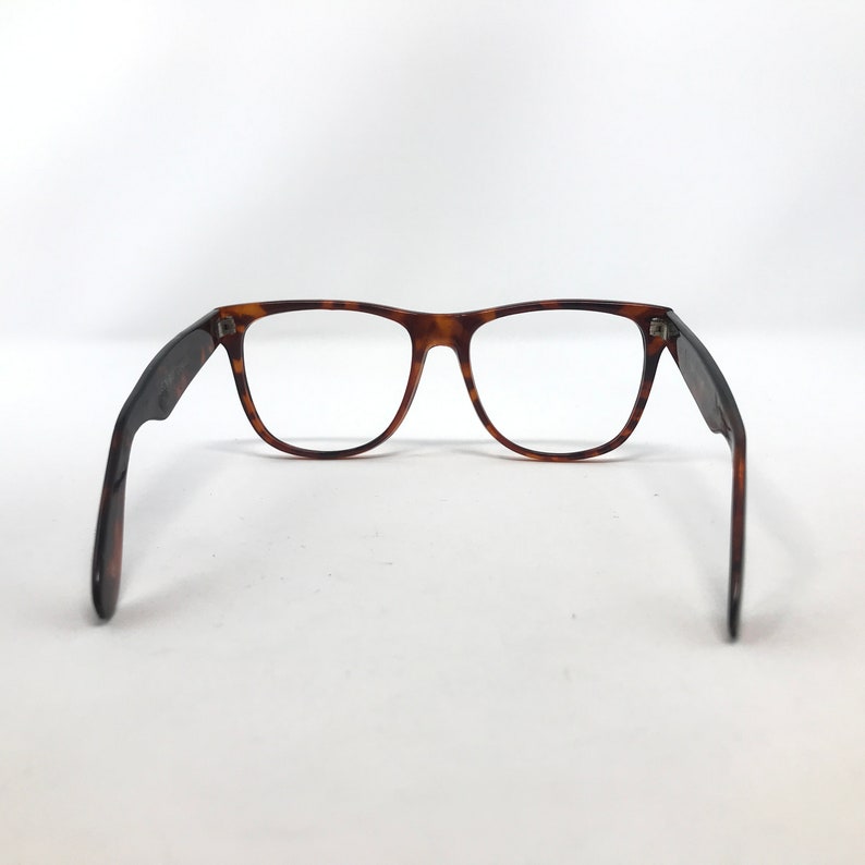 May include: Eyeglasses with a classic rectangular frame in a tortoiseshell pattern. The temples are dark brown and extend outward. The lenses are clear. The glasses are set against a white background.