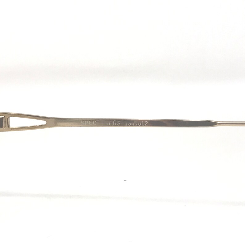 K&ouml;nnte beinhalten: Nahaufnahme eines silberfarbenen Brillengestells. Der Text "SPEC ERS 154.012" ist auf dem B&uuml;gel aufgedruckt. Das Gestell hat ein schlankes, modernes Design.