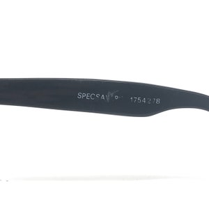 May include: Close-up of a black eyeglass frame arm with the text "SPECSAVERS" and the number "1754278" printed in white. The frame is made of a matte black material.