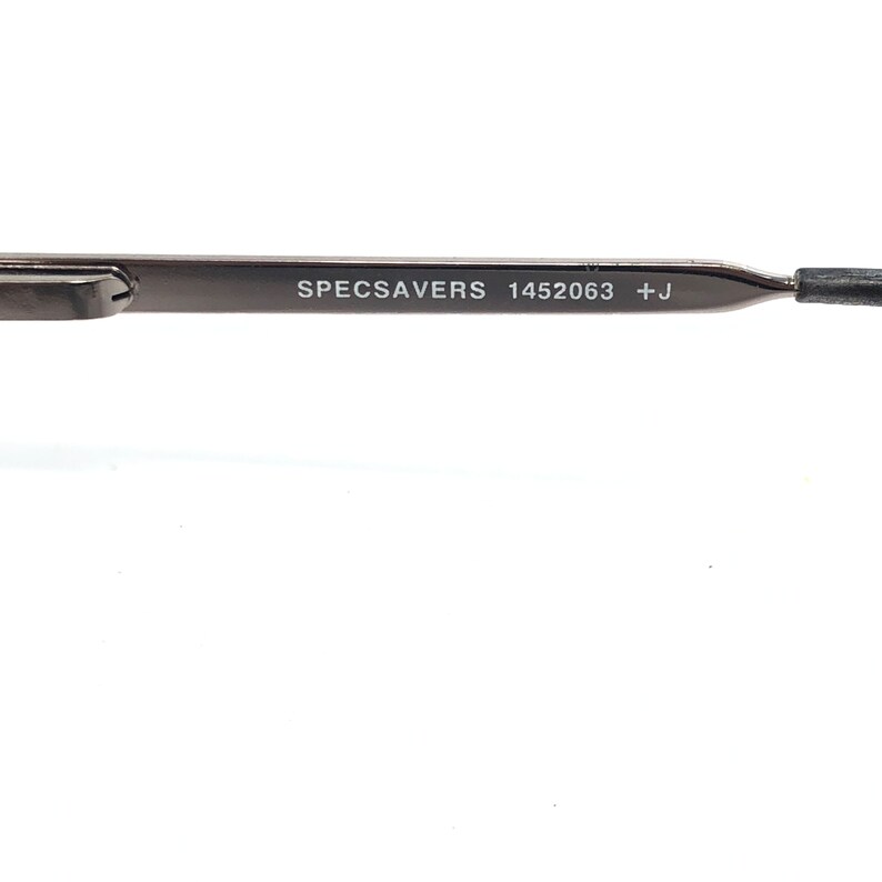 Peut inclure: Gros plan sur une branche de lunettes gris fonc&eacute; avec le texte "SPECSAVERS 1452063 +J" imprim&eacute; en blanc. La branche est fine et de conception moderne. Le fond est blanc.