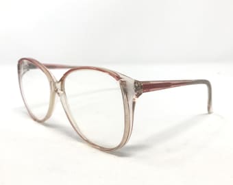 Könnte beinhalten: Transparente rosafarbene Brille aus Kunststoff mit abgerundeter quadratischer Form.
