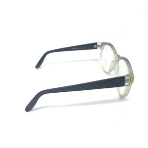 May include: Clear plastic framed glasses with black arms. The glasses have a gold accent on the side.