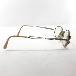 Peut inclure: Lunettes en m&eacute;tal dor&eacute; avec une monture ronde et des verres transparents. Les branches des lunettes sont en plastique beige.