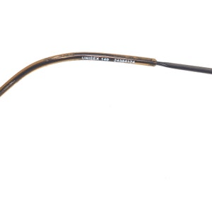 Puede incluir: Una parte de unas gafas con montura moteada marr&oacute;n y negra. El texto "UNISEX 149 24384124" est&aacute; impreso en la montura.