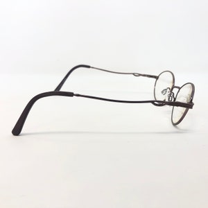 Peut inclure: Une paire de lunettes &agrave; monture ronde avec une monture en m&eacute;tal marron fonc&eacute;. Les lunettes ont un design fin et d&eacute;licat avec des branches incurv&eacute;es et un pont. Les verres sont clairs, et le style g&eacute;n&eacute;ral est minimaliste et classique.