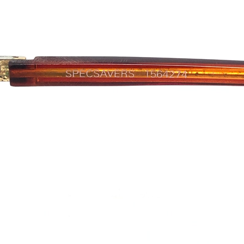 May include: Close-up of a brown and gold eyeglasses frame. The text "SPECSAVERS" and "T5642-74" are printed on the frame. The frame is set against a white background.