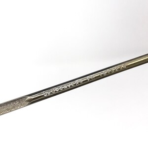 Puede incluir: Primer plano de un brazo de gafas de metal plateado con el texto "SPECSAVERS PM 1673294" grabado en &eacute;l.