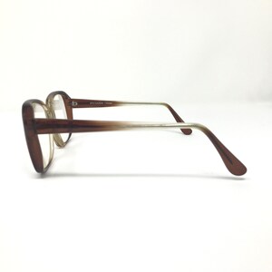 May include: Brown-framed eyeglasses with a classic design. The frames are a solid brown color, transitioning to a lighter shade towards the temples. The lenses are clear. The text "SPECSAVERS 1794294" is printed on the temple.