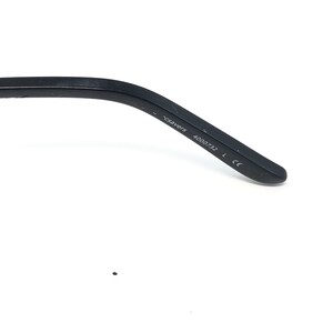 May include: Close-up of a black eyeglass arm with the text "csavers" and the number "4000732". The arm is made of a matte black material and has a curved design.