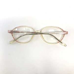 K&ouml;nnte beinhalten: Transparente ovale Brille aus Kunststoff mit rosa und silbernem Rand.
