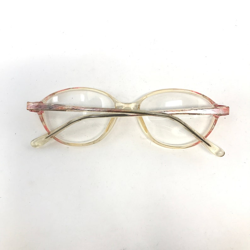 K&ouml;nnte beinhalten: Transparente ovale Brille aus Kunststoff mit rosa und silbernem Rand.