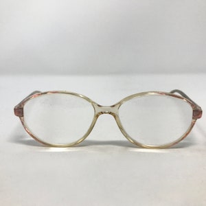 K&ouml;nnte beinhalten: Transparente ovale Brille aus Kunststoff mit einem rosa-wei&szlig;en Marmorrahmen.