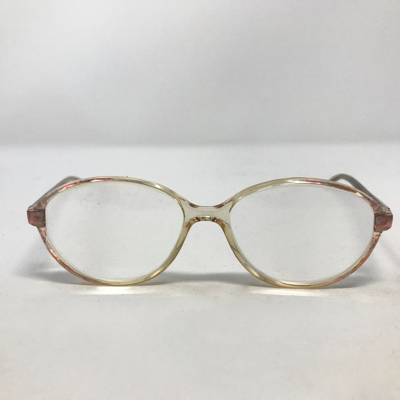 K&ouml;nnte beinhalten: Transparente ovale Brille aus Kunststoff mit einem rosa-wei&szlig;en Marmorrahmen.