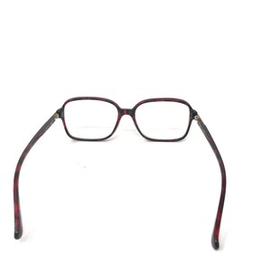 May include: Eyeglasses with a tortoiseshell pattern frame. The rectangular lenses are clear, and the temples are dark brown with red accents. The glasses are set against a white background.