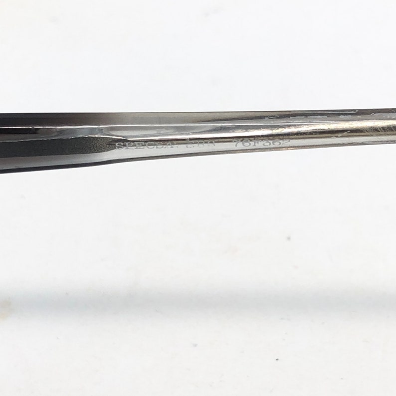 Op de afbeelding: Close-up van een zilveren metalen gereedschap met de tekst "SPECIA LBR 76F362" ge&euml;tst op het oppervlak. Het gereedschap heeft een taps toelopend ontwerp en lijkt te worden gebruikt voor precisiewerk. De achtergrond is wit.