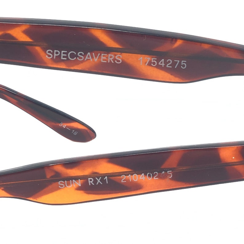 K&ouml;nnte beinhalten: Nahaufnahme des inneren Arms einer Brille mit Schildpattmuster. Auf dem B&uuml;gel steht der Text "SPECSAVERS 1754275". Auf dem anderen B&uuml;gel steht der Text "SUN RX1 21040245". Die Gr&ouml;&szlig;e ist 54-18.