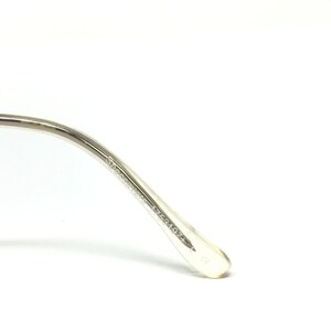 May include: Close-up of a silver-toned eyeglass frame arm. The arm has the text "Specsavers 1753197+" printed on it. The frame is made of a shiny, metallic material.