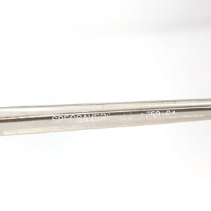 May include: Close-up of a clear eyeglass frame arm with the text "SPECSAVERS" and the numbers "758 84" printed in white. The frame arm is made of a transparent material.