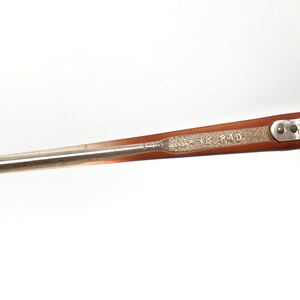May include: Close-up of a vintage eyeglasses frame. The frame is a light brown color with a silver metal arm. The text "940" is visible on the frame. The frame has a textured section with the text "55 18 R40".