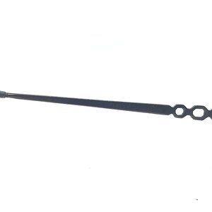 May include: A black clock hand with a tapered design. The hand has a small, round tip and a series of open, hexagonal shapes at the end. The object is set against a white background.