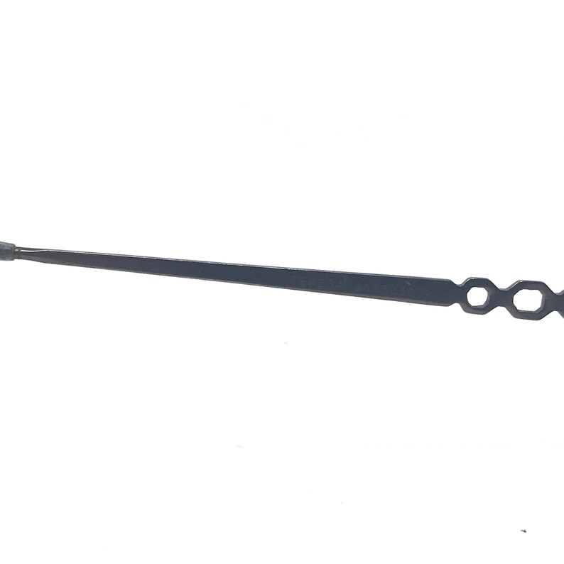 May include: A black clock hand with a tapered design. The hand has a small, round tip and a series of open, hexagonal shapes at the end. The object is set against a white background.