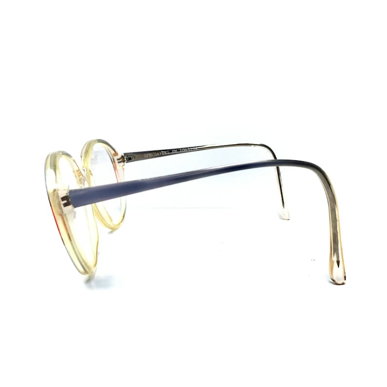 Puede incluir: Un par de gafas redondas, de pl&aacute;stico transparente, con patillas de metal azul. Las patillas est&aacute;n dobladas en un &aacute;ngulo de 90 grados y el texto "SPECSAVERS" est&aacute; impreso en la patilla derecha.