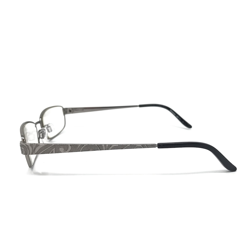 May include: Gray metal eyeglasses with a rectangular frame and black temples. The temples feature a decorative etched pattern. The lenses are clear. The glasses are designed for vision correction.
