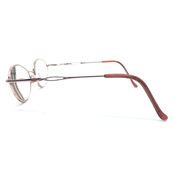 K&ouml;nnte beinhalten: Eine Brille mit runden Gl&auml;sern und einem d&uuml;nnen, silberfarbenen Rahmen. Die B&uuml;gel sind dunkelbraun. Die Brille ist vor einem wei&szlig;en Hintergrund abgebildet.