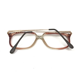 K&ouml;nnte beinhalten: Eine Brille aus braunem und klarem Kunststoff mit einem silbernen Metallrahmen. Die B&uuml;gel der Brille sind schwarz.