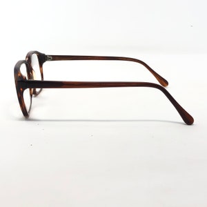 May include: A pair of eyeglasses with a tortoiseshell pattern on the frames. The frames are a mix of brown and amber hues. The temples are a solid brown color, and the lenses are clear.