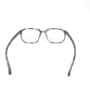 Puede incluir: Gafas con montura rectangular con estampado gris y blanco. Las gafas tienen un dise&ntilde;o cl&aacute;sico con un patr&oacute;n sutil en la montura y las patillas. Las lentes son transparentes y las patillas se curvan suavemente.