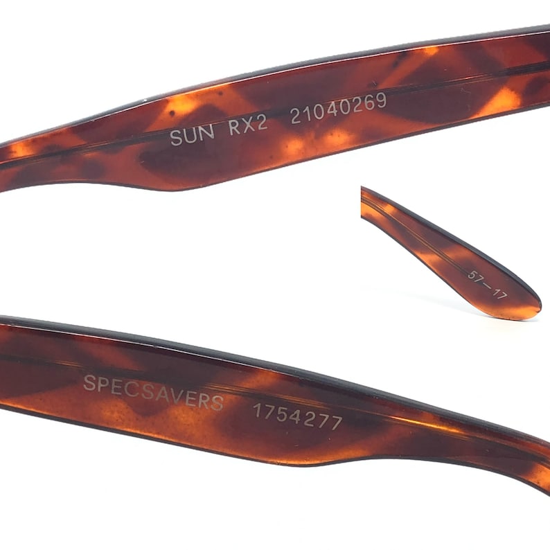 May include: Close-up of the arm of a pair of brown tortoiseshell sunglasses. The text "SUN RX2 21040269" is printed on the arm. The other arm has the text "SPECSAVERS 1754277" printed on it. The end of the arm has the numbers "57-17".