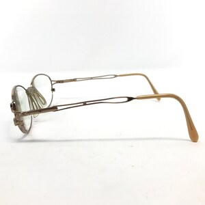 Peut inclure: Une paire de lunettes en m&eacute;tal dor&eacute; avec un double pont et des embouts de branches en plastique brun.
