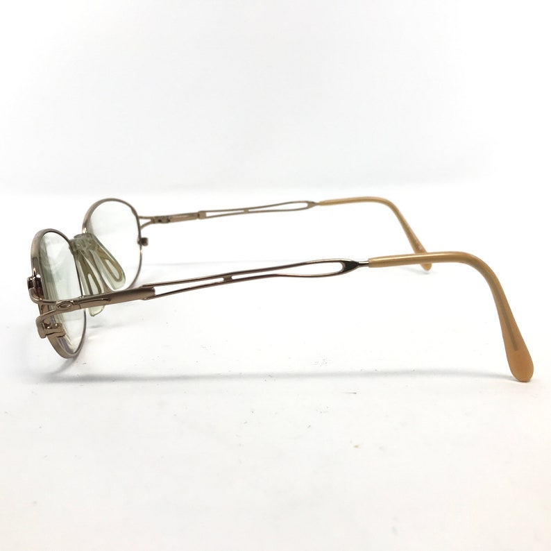 Peut inclure: Une paire de lunettes en m&eacute;tal dor&eacute; avec un double pont et des embouts de branches en plastique brun.
