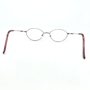 K&ouml;nnte beinhalten: Oval geformte Brille mit einem d&uuml;nnen, dunkelbraunen Metallrahmen. Die B&uuml;gel sind dunkler braun mit Schildpattmuster. Die Gl&auml;ser sind klar, und der Nasensteg ist silberfarben. Die Brille ist vor wei&szlig;em Hintergrund.