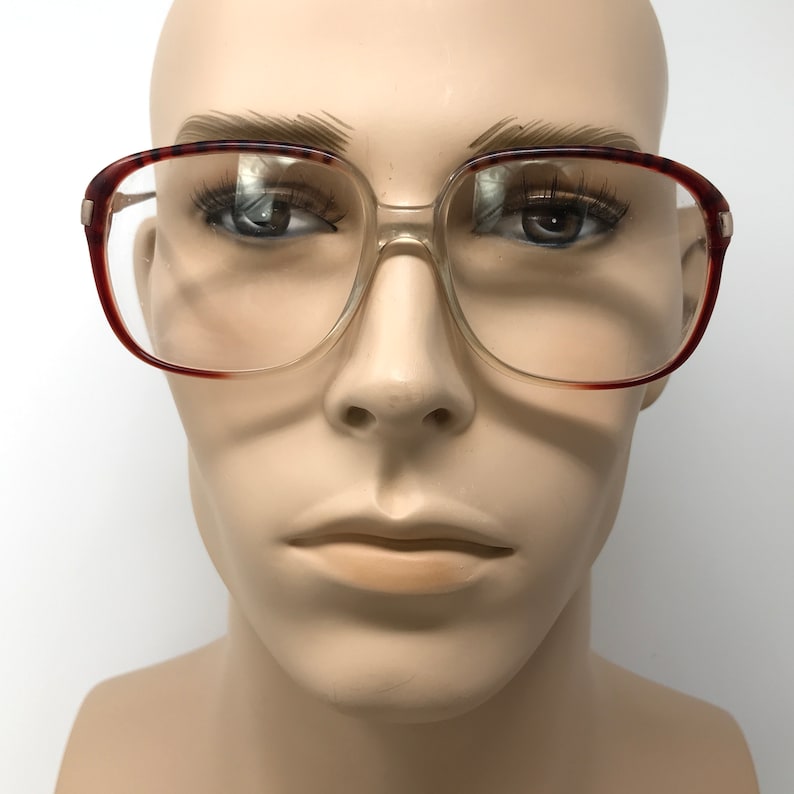K&ouml;nnte beinhalten: Eine Brille mit klaren, &uuml;bergro&szlig;en Gl&auml;sern und einem Schildpattgestell. Die Brille sitzt auf einem Mannequin-Kopf.