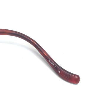May include: Close-up of the brown plastic arm of a pair of glasses. The arm is marked with the text "W033 L CE".