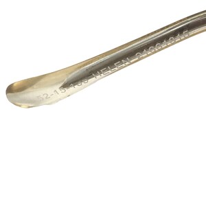 K&ouml;nnte beinhalten: Nahaufnahme des B&uuml;gels einer Brille mit dem eingravierten Text "52-15-138 HELEN 24C4145" auf dem Metall.